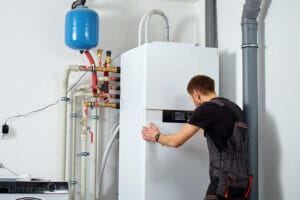 Technician installing heat pump system with pipes and expansion tank